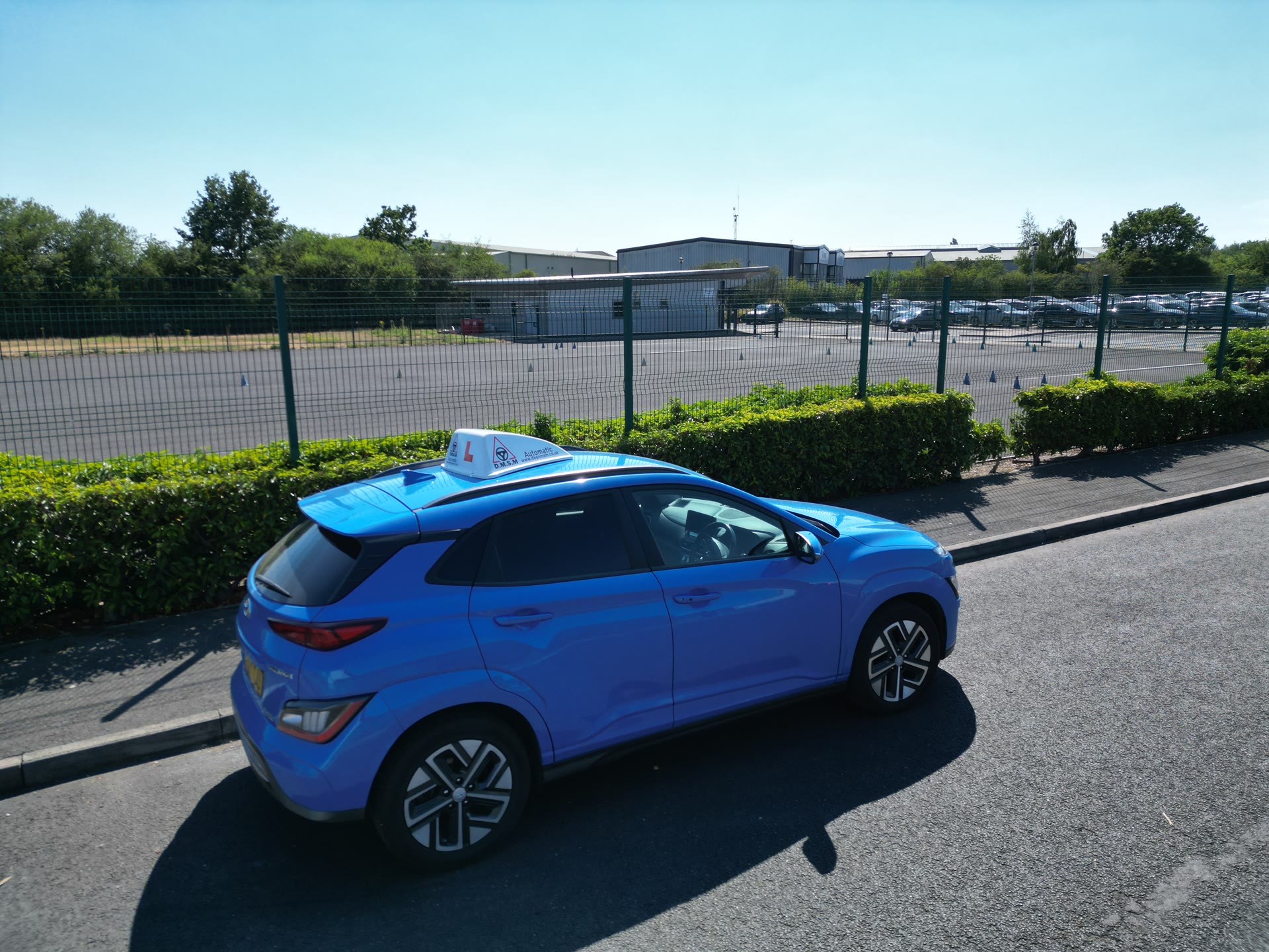 Dean MSM blue automatic tuition car beside a driver training area in Lincoln